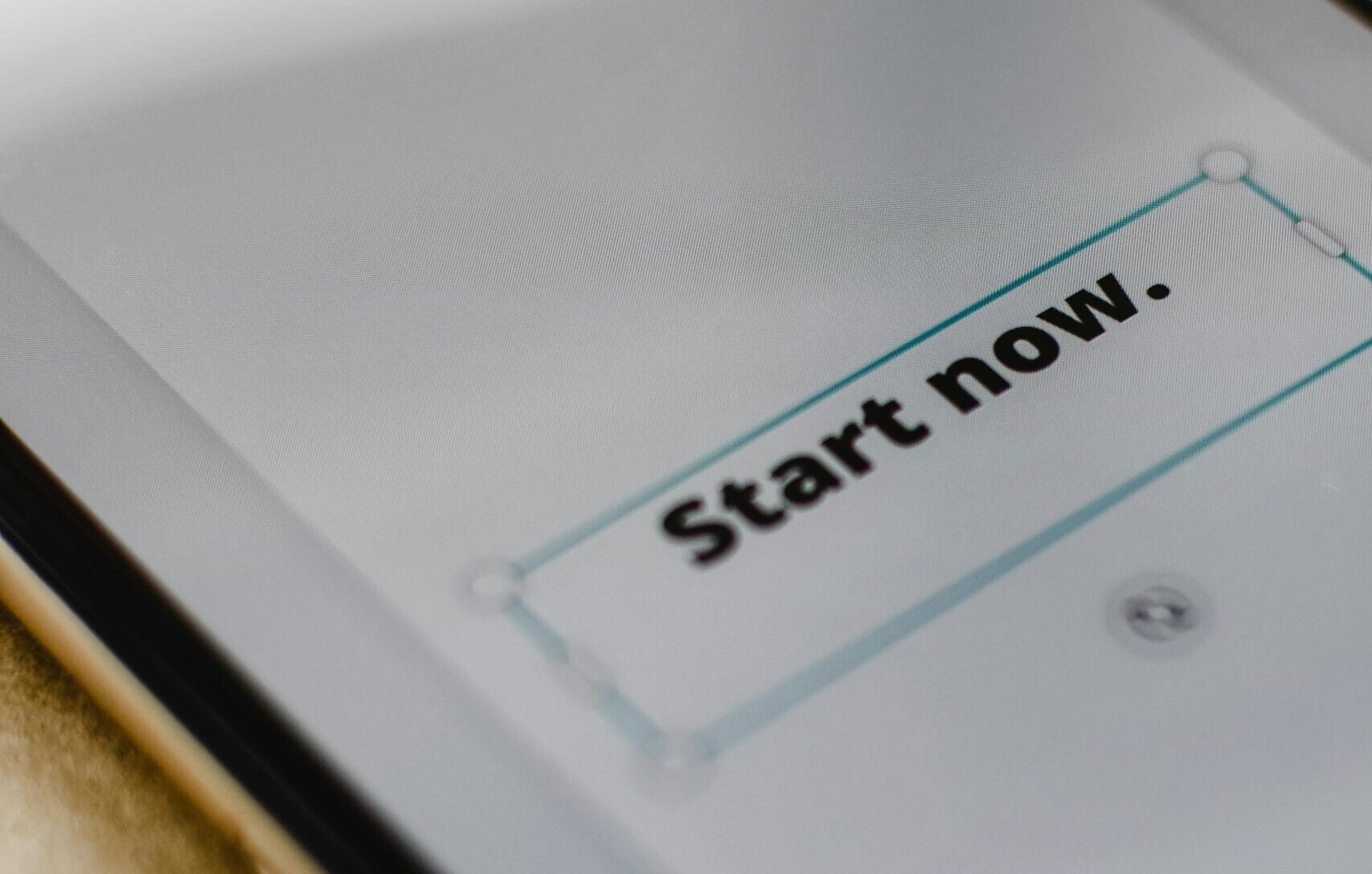 A close-up photo of a smartphone displaying 'Start Now', emphasizing digital interaction.